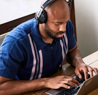 A man with headphones on working on his laptop