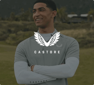 Eine lächelnde Person trägt ein graues Castore-Sportoberteil. Darüber steht das Castore-Logo.