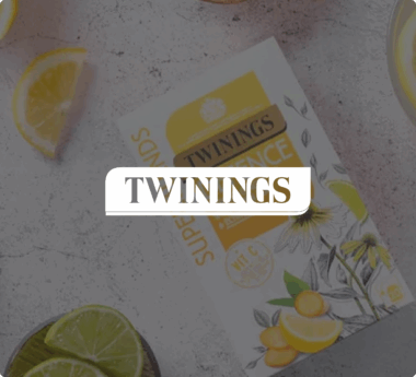 Caja de té de Twinings con rodajas de limón y gajos de lima sobre una superficie texturizada