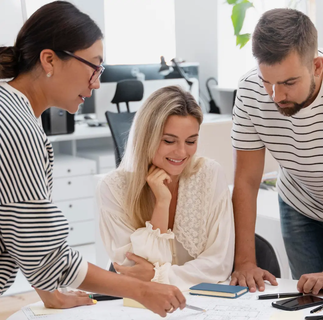 Three people in a modern office, jotting down notes and collaborating on ideas.